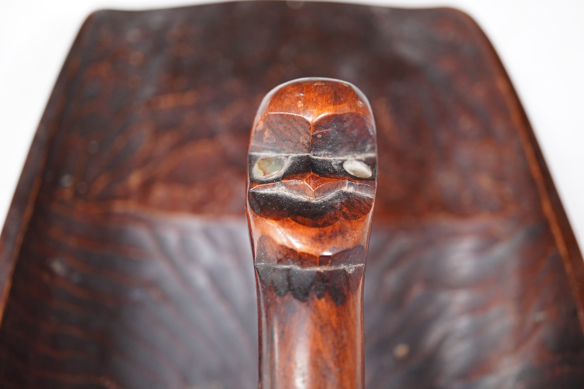 A carved Maori ta ta (water bailer) with mother of pearl inlay, 33cm long. Condition - good